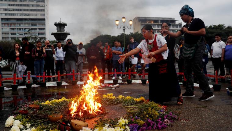 GU2005. CIUDAD DE GUATEMALA (GUATEMALA), 08/10/2019.- . Una niña aviva el fuego ceremonial este martes durante una ceremonia para reinstalar un altar en memoria de 41 niñas que murieron quemadas en un hogar estatal de Guatemala, en la capital. En el mismo lugar de antes, varias organizaciones de mujeres y de la sociedad civil se reunieron en el Parque Central, en la Plaza de la Constitución, para poner las 41 cruces, de color rojo, en recuerdo de las 41 niñas muertas en el Hogar Seguro Virgen de la Asunción el 8 de marzo de 2017. EFE/Esteban Biba