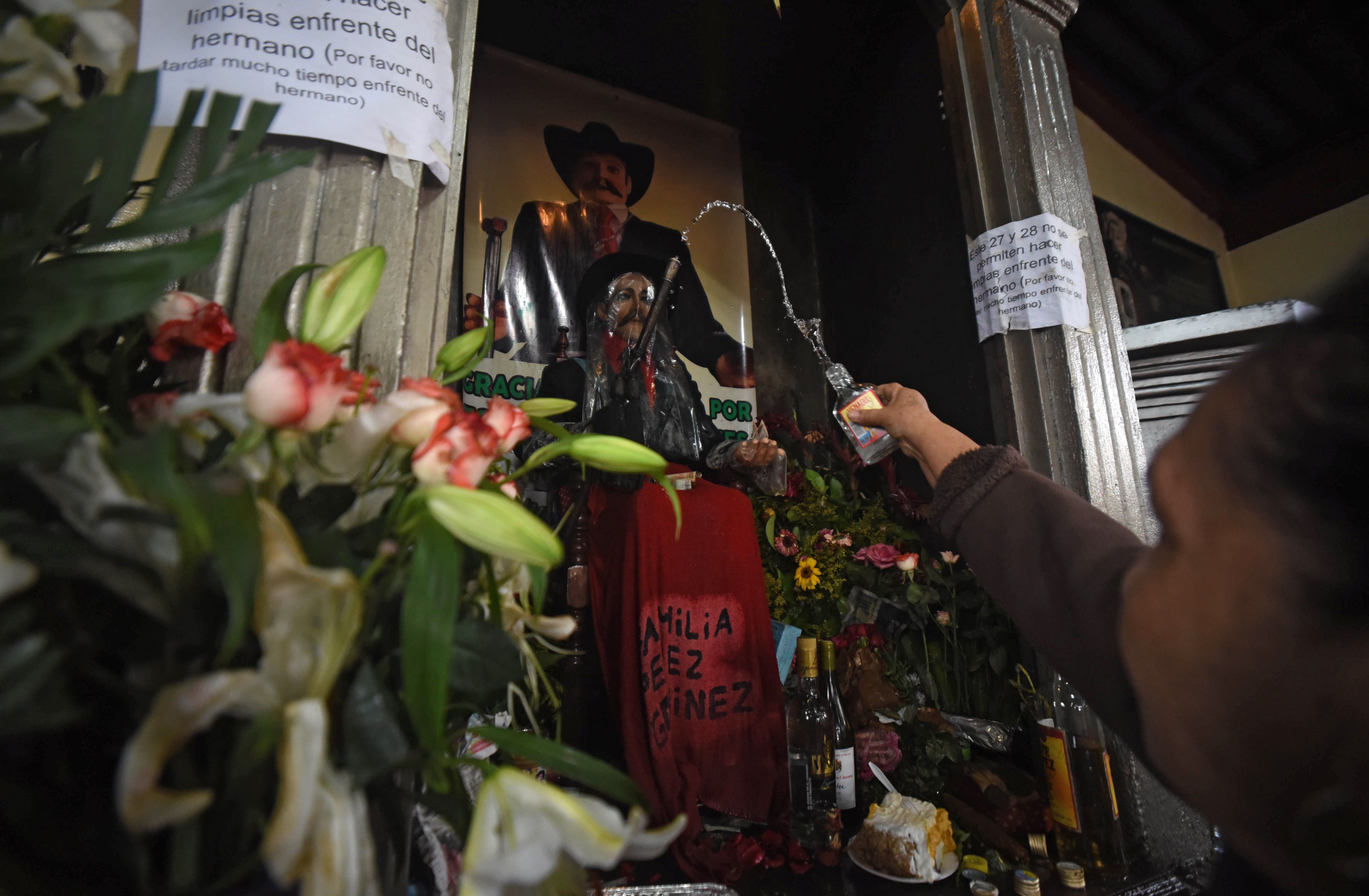 
La imagen de madera de San Simón es cubierta con un plástico transparente durante su celebración. (Foto Prensa Libre: AFP)
