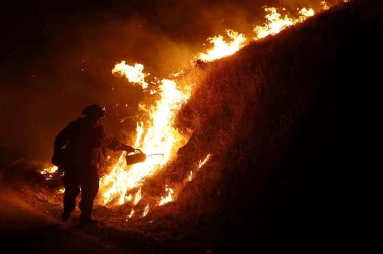 Bomberos locales intentan apagar el fuego. (Foto Prensa Libre: AFP)