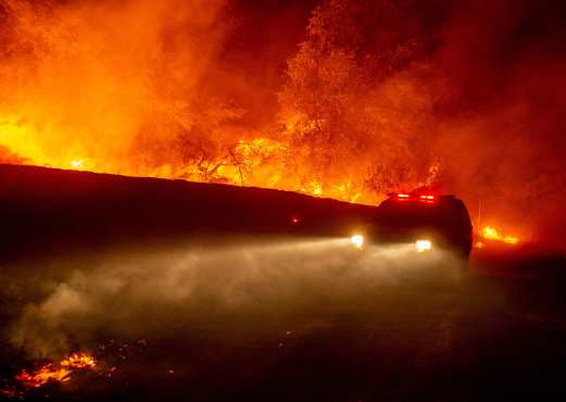 Un camión de bomberos atraviesa las llamas durante el incendio. (Foto Prensa Libre: AFP) 