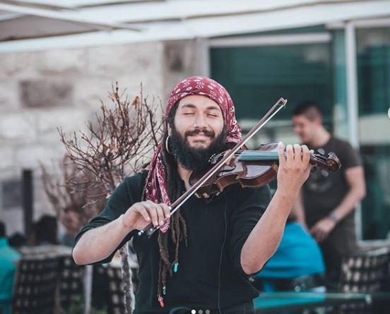 El músico guatemalteco Abdul Medina ejecuta su violín en Budva, Montenegro. (Foto Prensa Libre: Tomada de Instagram).