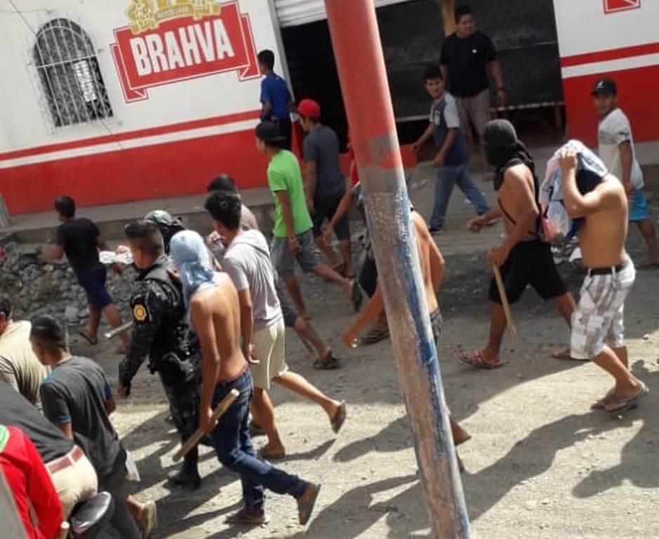 Turba con rostro cubierto y armada de palos toma como rehén a un policía. (Foto Prensa Libre: Cortesía)