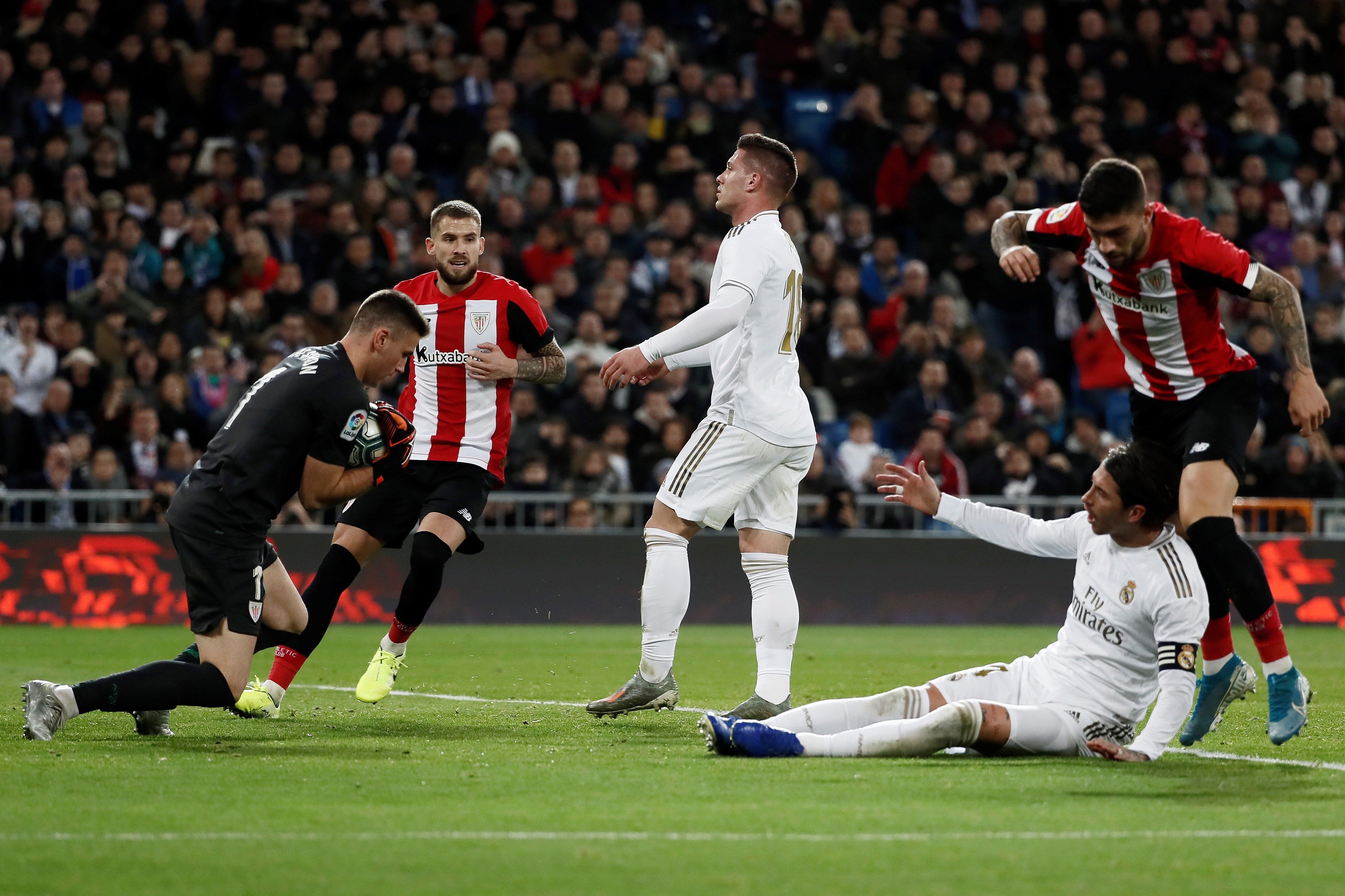 El portero del Athletic de Bilbao Unai Simón (i) detiene un balón ante Luka Jovic (c) y Sergio Ramos durante el partido de Liga en el estadio Santiago Bernabéu. (Foto Prensa Libre: EFE).