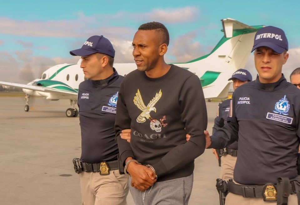 Fotografía cedida por la Policía de Colombia que muestra el momento en el que agentes de la Interpol trasladan al exfubolista internacional Jhon Viáfara (c) a un avión para su extradición hacia EE.UU. (Foto Prensa Libre: EFE)