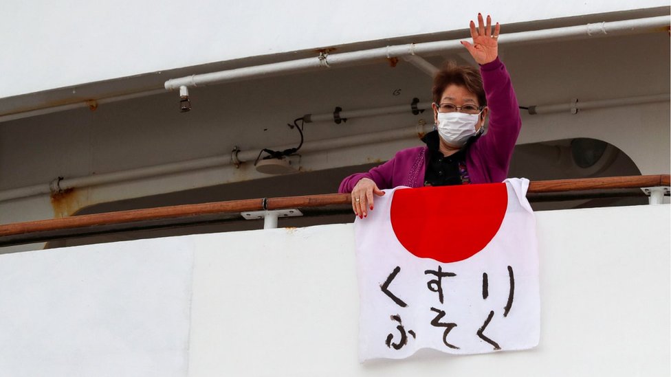 Una pasajera del crucero Dream Princess exhibe una bandera japonesa en la que alerta sobre la falta de medicamentos. (Foto Prensa Libre: Reuters)