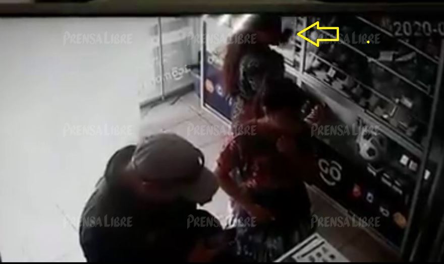 Momento en que una mujer sustrae un celular de una vitrina de un comercio en Almolonga, Quetzaltenango. (Foto Prensa Libre: Toma de video)