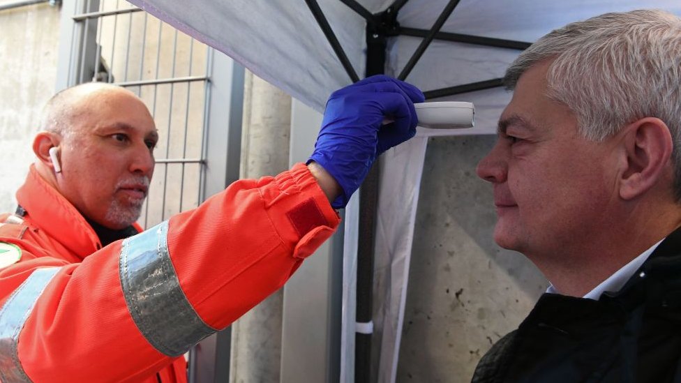 Las pocas personas que pueden acceder a los partidos de fútbol tienen que medirse la temperatura antes de entrar en el estadio.