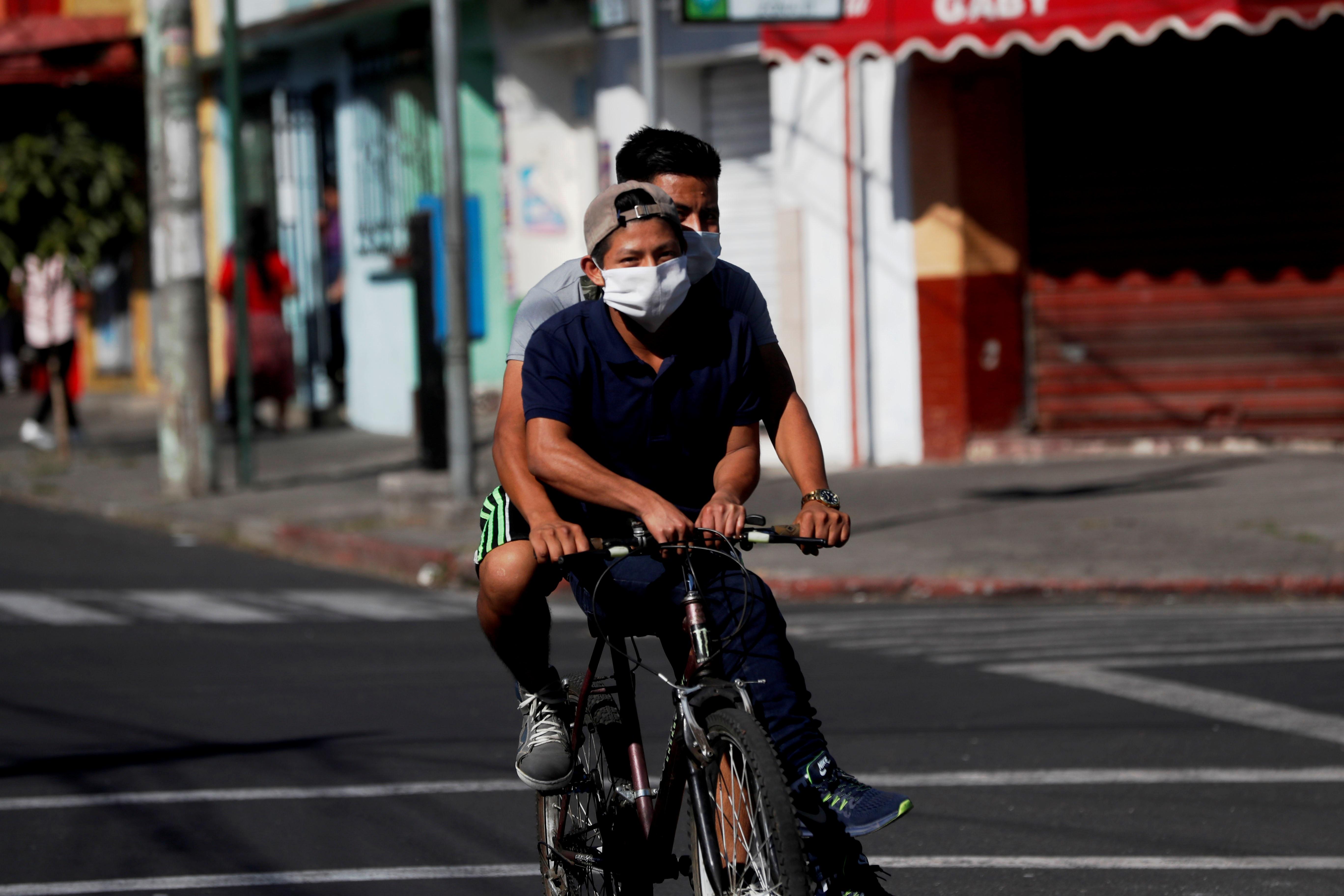 Jóvenes montan en una bicicleta antes del comienzo del toque de queda  en Guatemala. (Foto Prensa Libre: EFE)