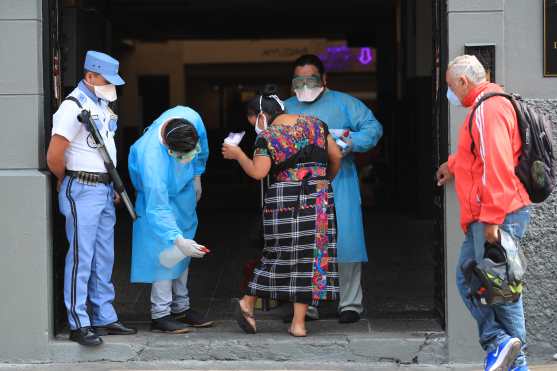 Trabajadores del Patronato Dr. Roberto Koch toman la temperatura, aplican alcohol en gel en las manos y desinfectan los zapatos de todos aquellos que ingresan a sus instalaciones. Foto Prensa Libre: Juan Diego González