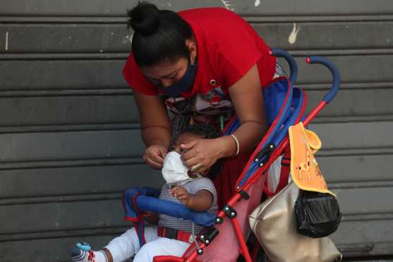 Benjamin es un niño de ocho meses de edad que no se acostumbra aún a llevar su mascarilla, aunque su mamá hace el intento porque la porte mientras caminan por la zona 1 de Guatemala. Foto Prensa Libre: Óscar Rivas