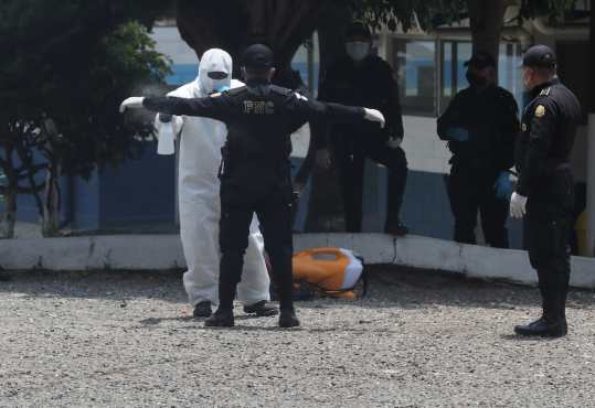 Médicos y agentes de la Policía Nacional Civil son desinfectados en el albergue Ramiro de León Carpio, zona 13,  donde se encuentran personas deportadas de Estados Unidos que serán examinados para descartar que tengan Coronavirus. Foto Prensa Libre: Érick Ávila 