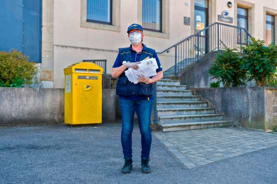 La francesa Aline Alemi, de 53 años, posposa, posa para una foto con letras frente a la oficina de correos en Angevillers, este de Francia, el 23 de abril de 2020, el día 38 de un estricto encierro destinado a frenar la propagación del nuevo COVID-19. Foto Prensa Libre: AFP