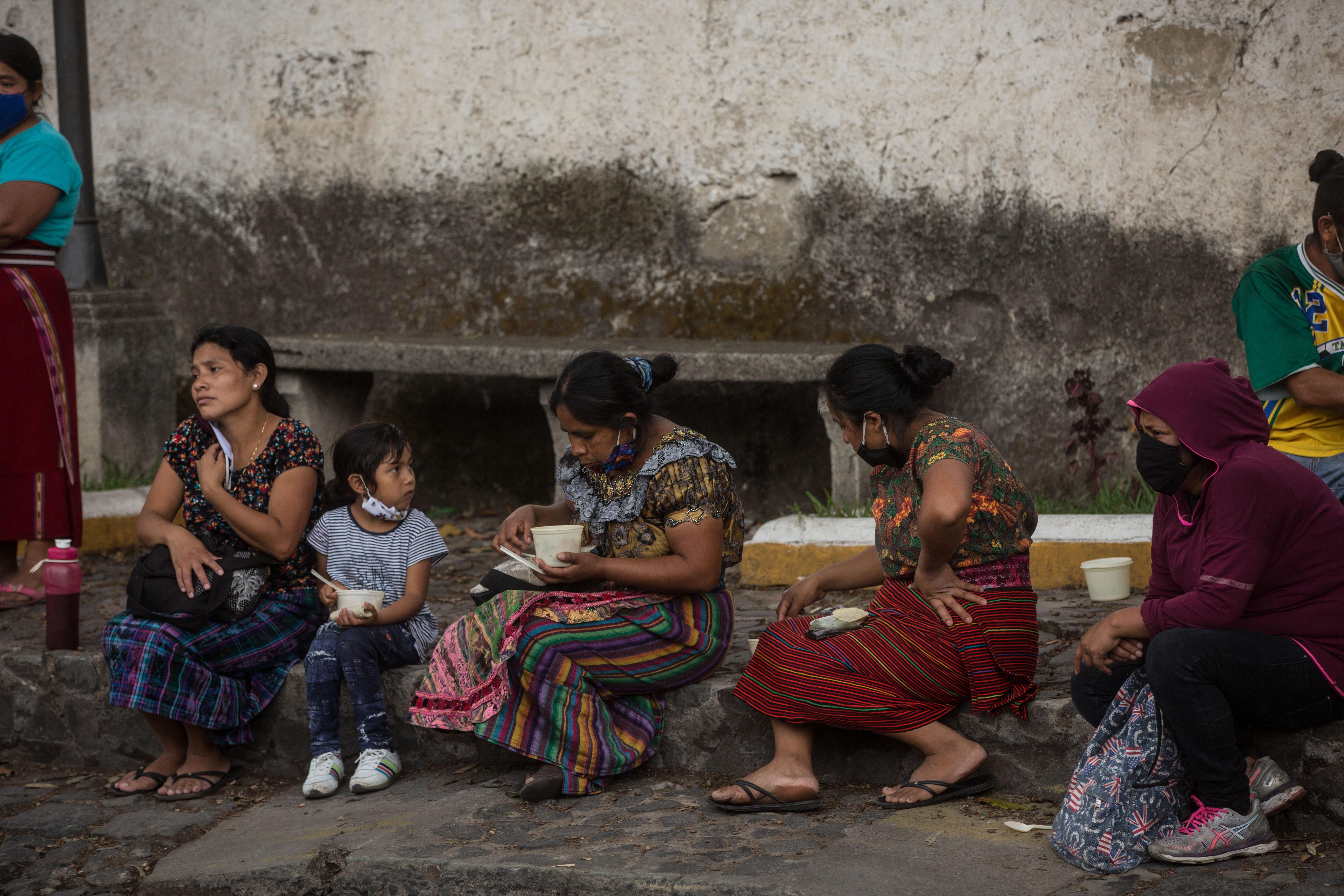 Fotografía del 29 de mayo de 2020 que muestra unas personas después de recibir almuerzos gratuitos de la organización Banderas Blancas Sacatepéquez, en el centro cultural Casa del Río en Antigua (Guatemala). (Foto Prensa Libre: EFE)