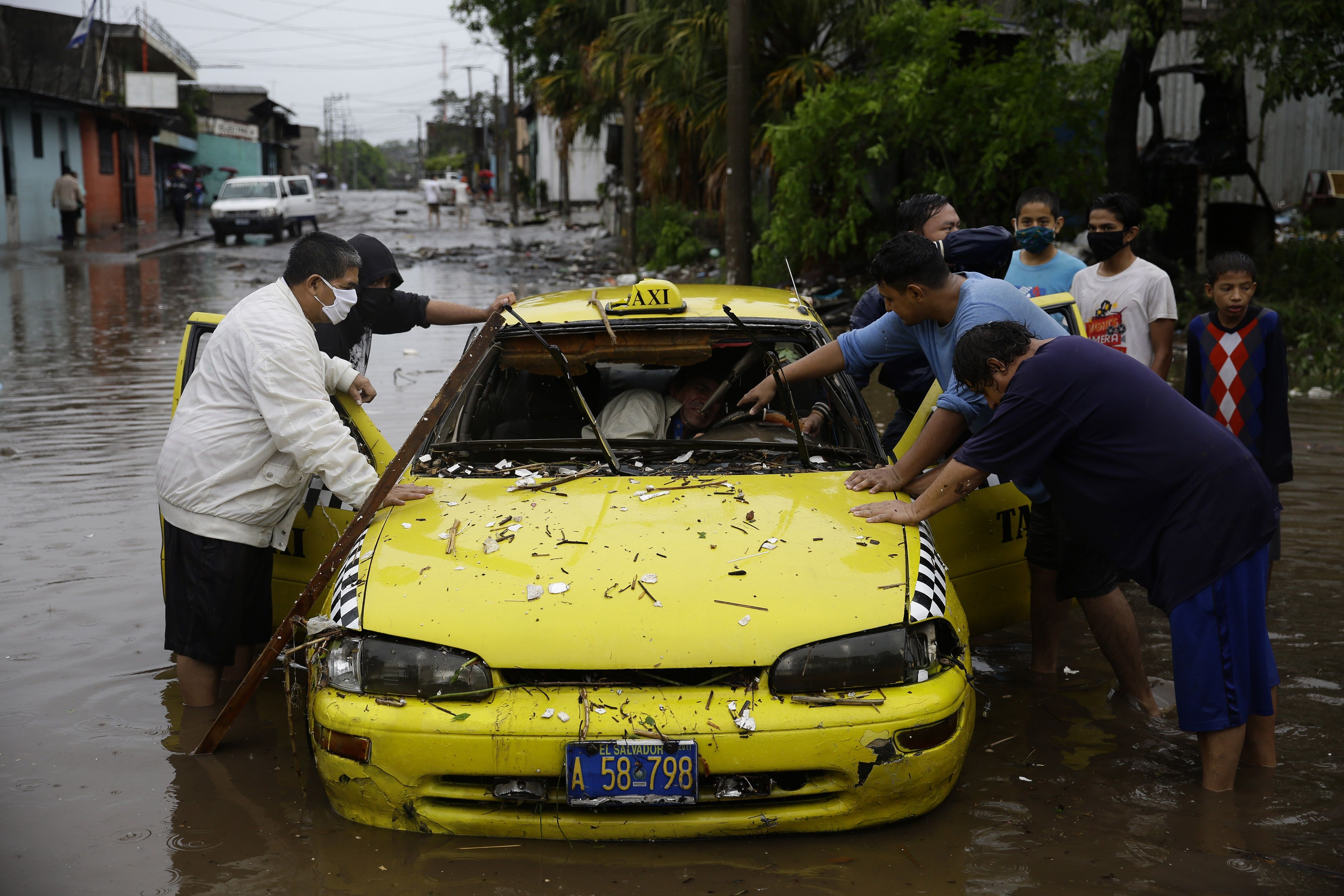 Residentes intentan empujar un taxi este domingo en una inundada calle de San Salvador (El Salvador), por las intensas lluvias generadas por la tormenta Amanda a su paso por la región. (Foto Prensa Libre: EFE)