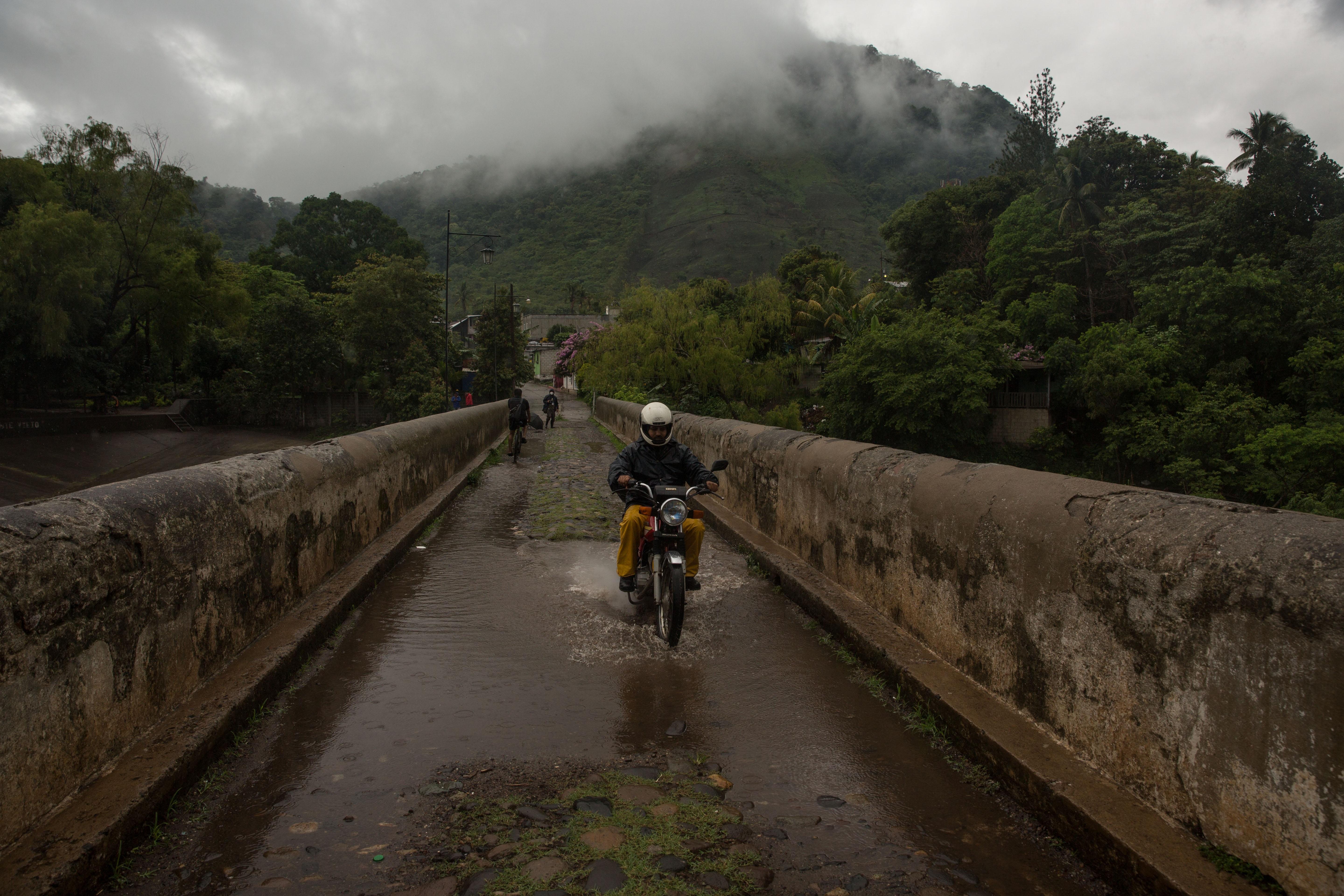 AME3435. CUILAPA (GUATEMALA), 31/05/2020.- Un motociclista cruza este domingo un puente sobre el río Los Esclavos, con una subida significativa de su caudal por las continuas lluvias provocadas por la tormenta tropical Amanda, en Cuilapa (Guatemala). La Coordinadora Nacional para la Reducción de Desastres (CONRED) mantiene la alerta roja por lluvias en Guatemala y ha habilitado varios albergues en caso de evacuaciones. EFE/Esteban Biba