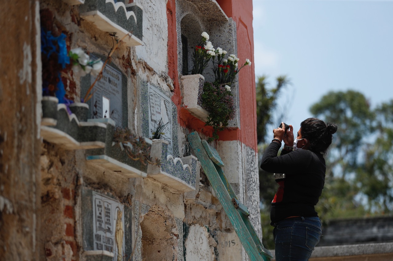 Uno de los colaboradores toma la foto de una tumba para mostrarla a uno de los deudos, que espera afuera del cementerio. (Foto Prensa Libre: Esbin García)