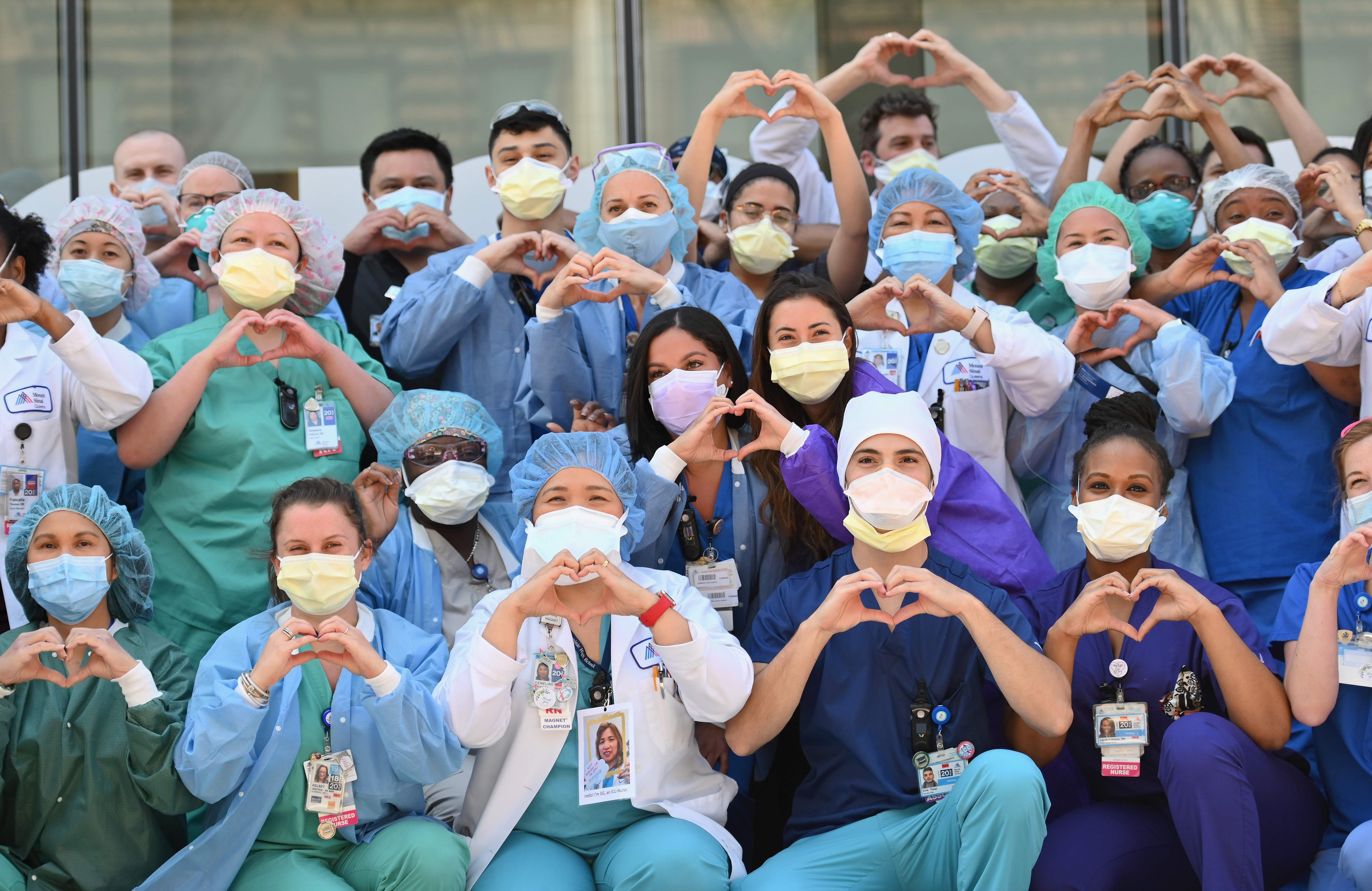 Enfermeros y encargados de la salud realizan con sus manos un gesto de corazón en celebración por el Día Internacional de la enfermera en las afueras del hospital Mt. Sinai Queen, en Nueva York. Fotografía Prensa Libre: Angela Weiss / AFP. 