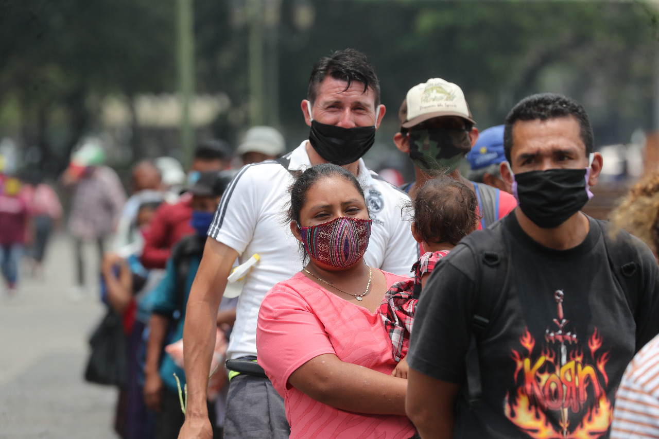 Una señora carga a su hija mientras hace fila para recibir alimentos. Foto: Erick Ávila