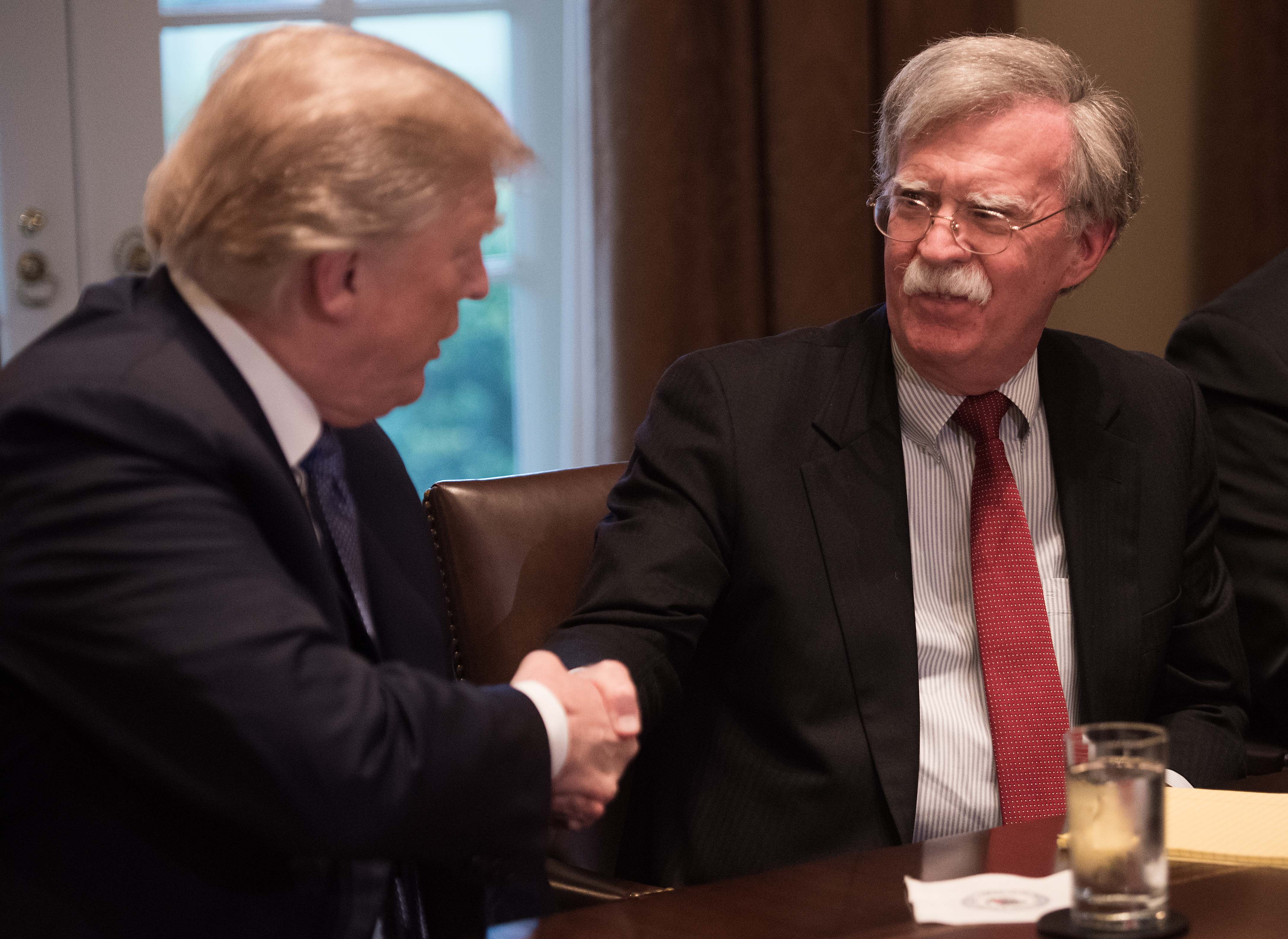 En esta foto de archivo tomada el 09 de abril de 2018, el presidente de los Estados Unidos, Donald Trump, se da la mano con el asesor de seguridad nacional John Bolton durante una reunión con altos líderes militares en la Casa Blanca en Washington, DC. (Foto Prensa Libre: AFP)