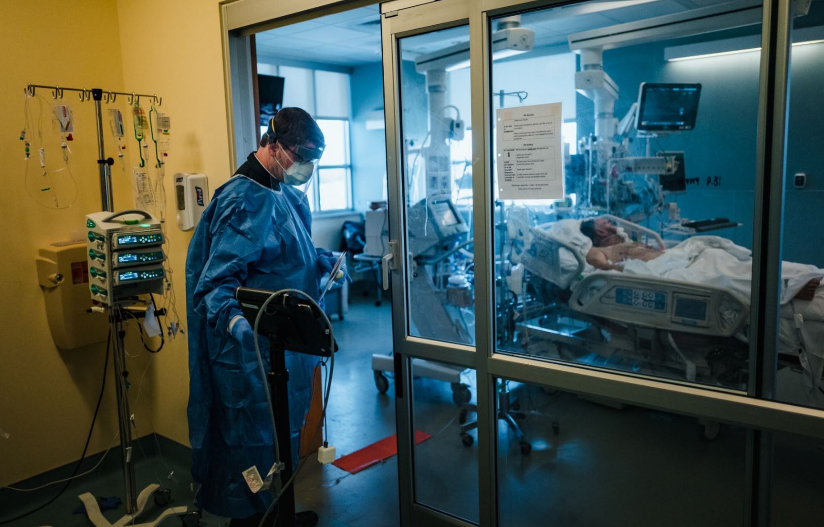 El padre Ryan Connors introduce un iPad en la UCI para que un familiar de un paciente con COVID-19 pueda verlo administrando la Unción de los enfermos, en el Centro médico de St. Elizabeth en Brighton, Massachusetts. (Foto Prensa Libre: The New York Times)