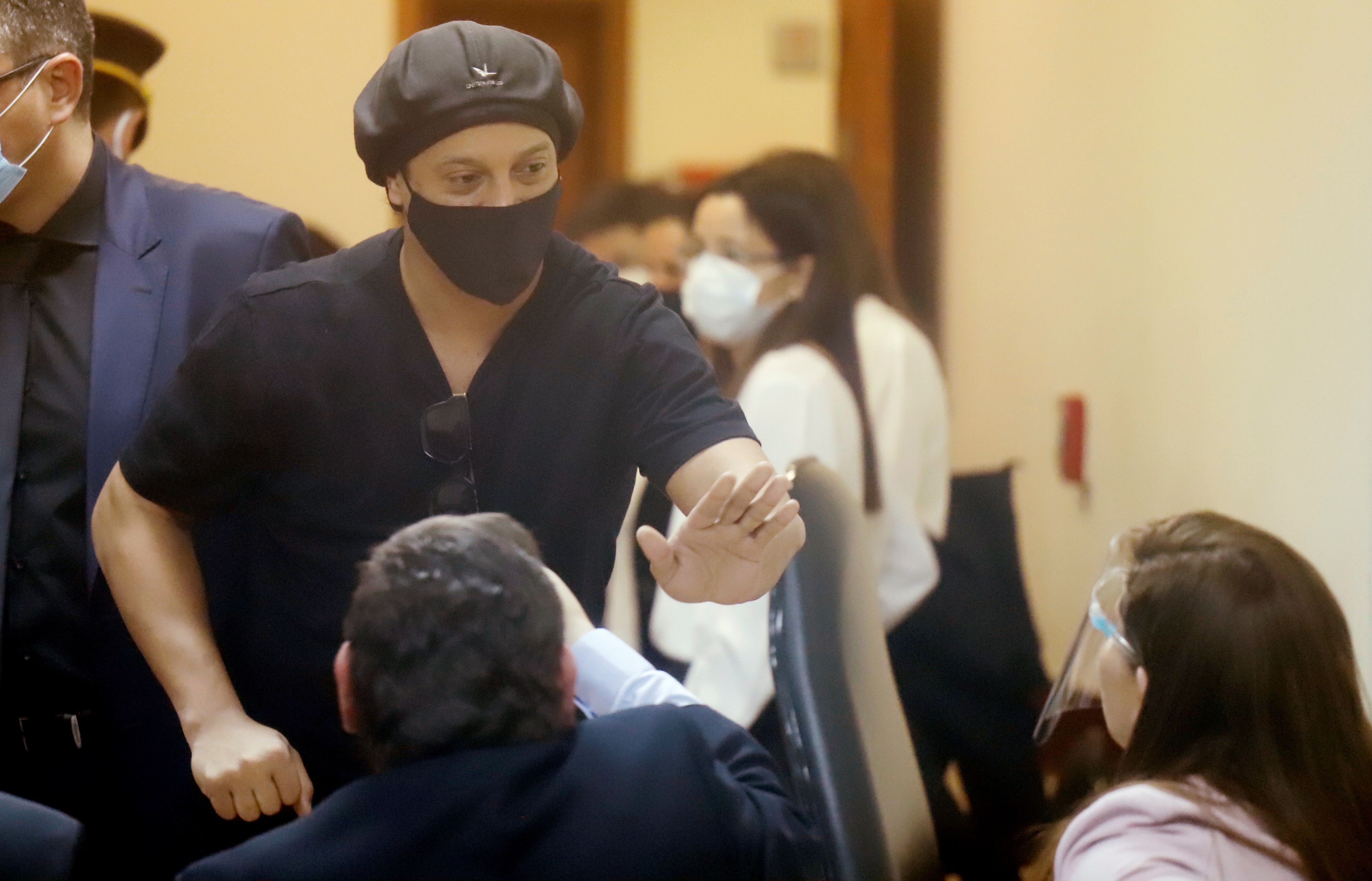 El exfutbolista brasileño Ronaldinho Gaúcho se despide de los fiscales al final de una audiencia en el Palacio de Justicia en Asunción, Paraguay. (Foto Prensa Libre: EFE)