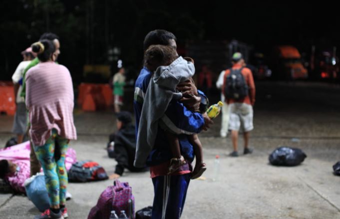 Hondureño -vestido de azul - sostiene a su hija de 5 años que viaja en la caravana y está a cargo de su sobrina de 1 año. (Foto Prensa Libre: Carlos Hernández)