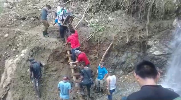 Personas ayudan a trasladar aun adulto mayor ante la falta de carreteras que comunican a la aldea Palo Grande, en Chiantla. (Foto Prensa Libre)