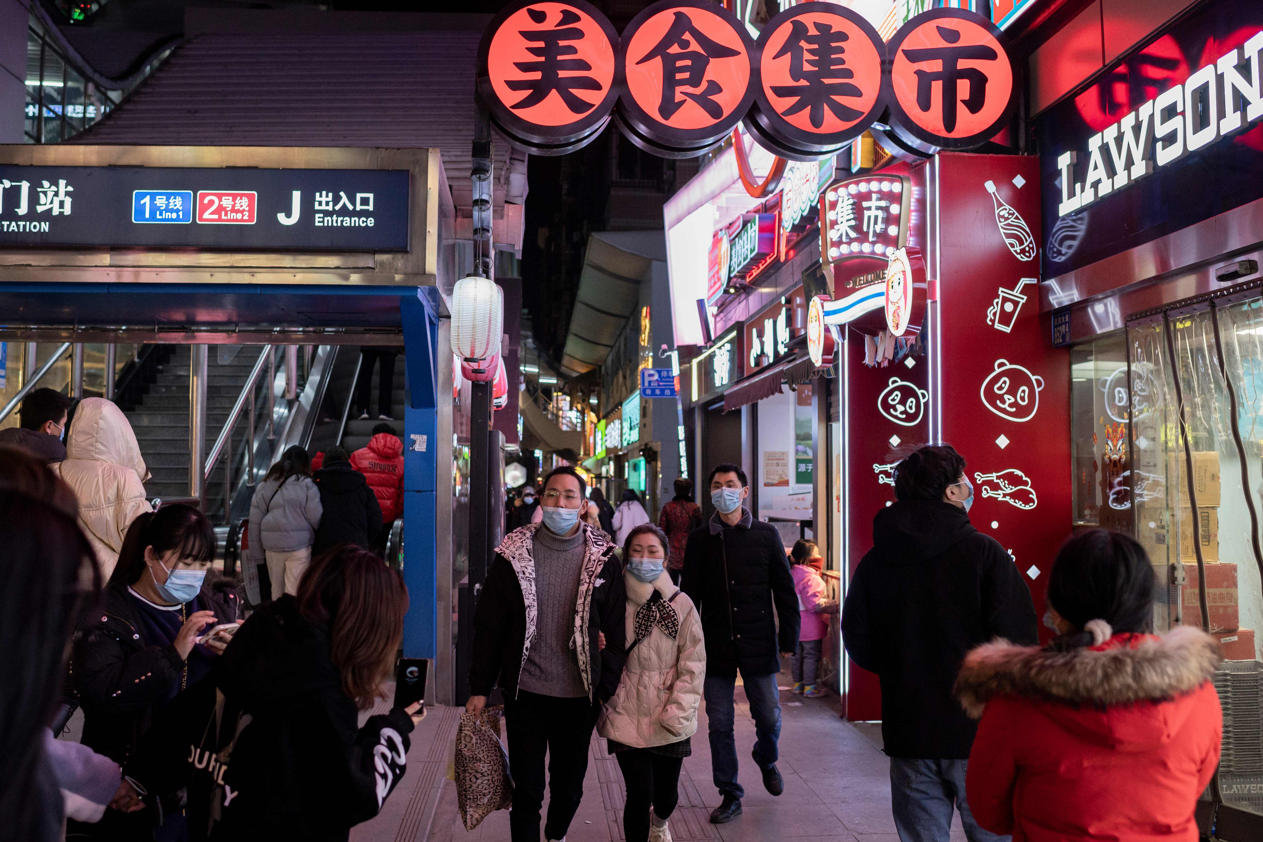 Pobladores usan mascarilla en una de las calles de Wuhan, China, a donde llegará un equipo de la OMS a investigar el origen del coronavirus. (Foto Prensa Libre: AFP)