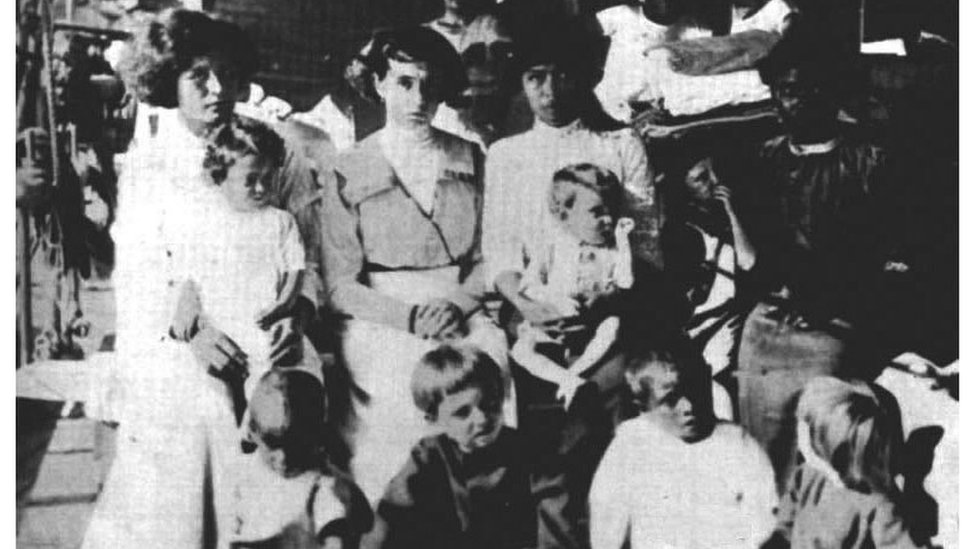 Las 11 sobrevivientes de Clipperton (tres adultas, una adolescente y siete niños pequeños) en el buque USS Yorktown que las rescató en 1917. (Adultas de izquierda a derecha: Tirsa Rendón, Alicia Arnaud y Altagracia Quiroz. Entre los ocho menores están los cuatro hijos de Alicia, Alicia, Ramón, Lydia y Angel, la hija de Tirsa, Guadalupe, y tres niños huerfanos, Francisco y Antonio Irra y la adolescente Rosalia Nava (arriba derecha).