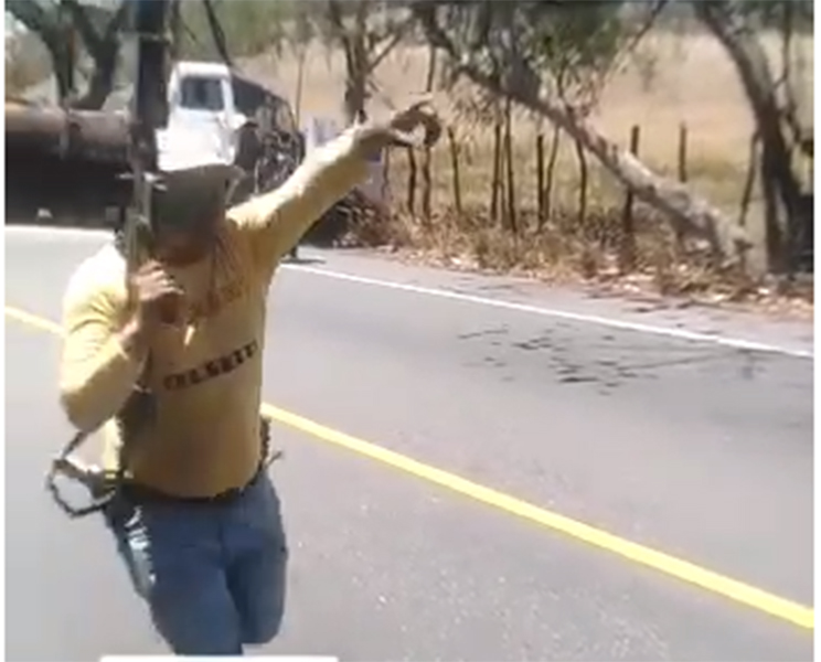 Un hombre no identificado porta un fusil de grueso calibre en la escena donde ocurrió un tiroteo en Gualán.