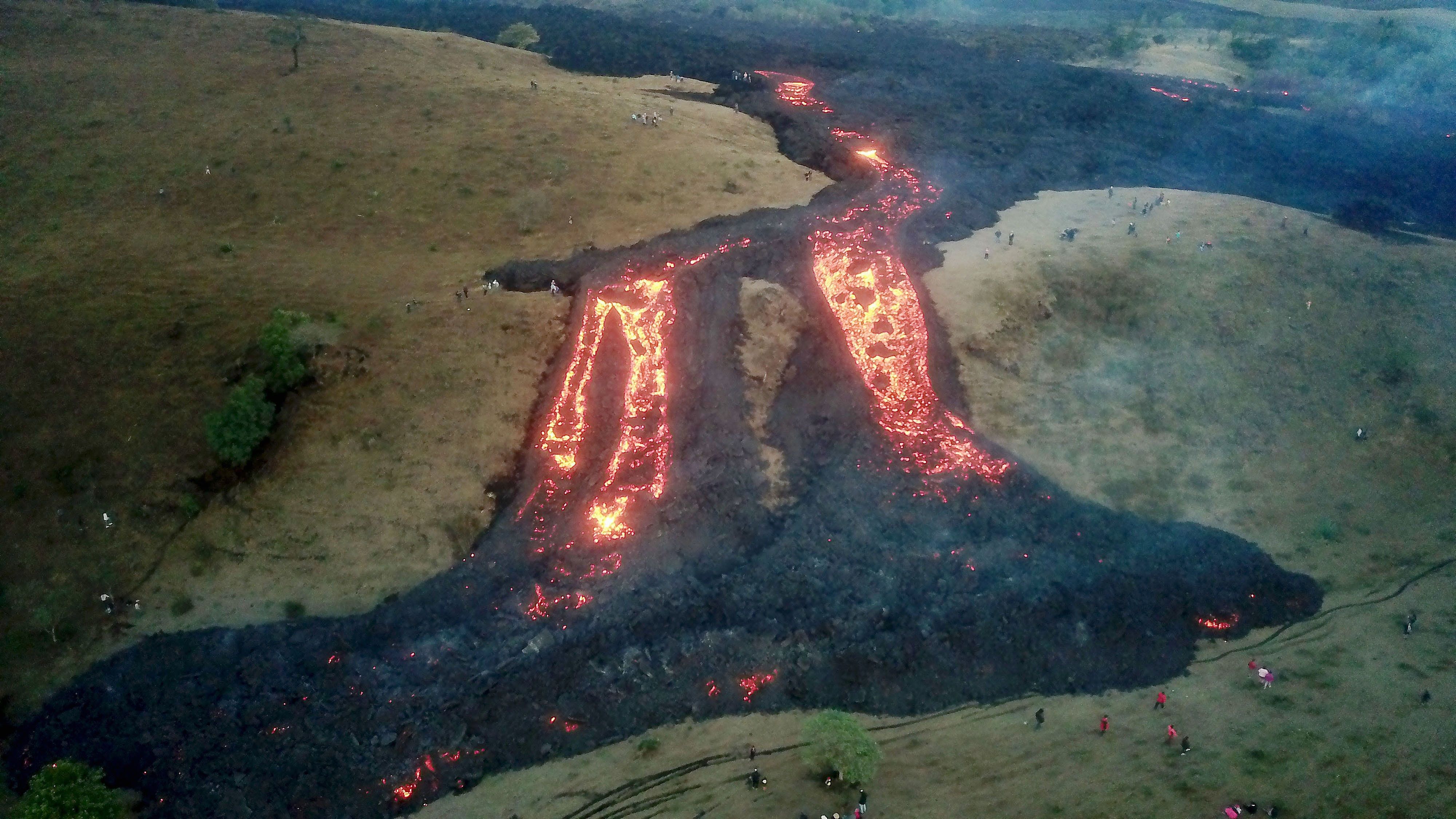 Vista aérea hoy desde un dron que muestra personas alrededor de uno de los ríos de lava causados por el volcán de Pacaya, el 13 de abril de 2021 desde la aldea El Patrocinio de San Vicente Pacaya. (Foto Prensa Libre: EFE)