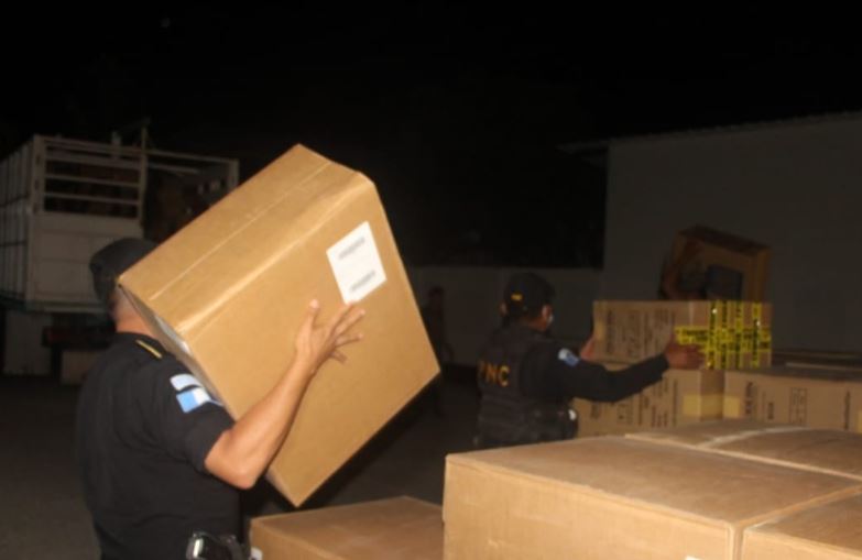 Agentes de la PNC custodian parte de los cigarrillos decomisados en Petén. (Foto Prensa Libre: PNC)
 
