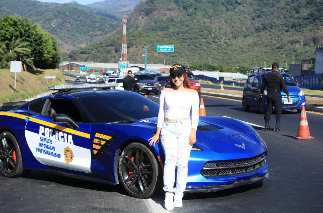 Una joven se toma una fotografía frente a la patrulla de la PNC portando una gorra de la institución policiaca. (Foto: PNC) 