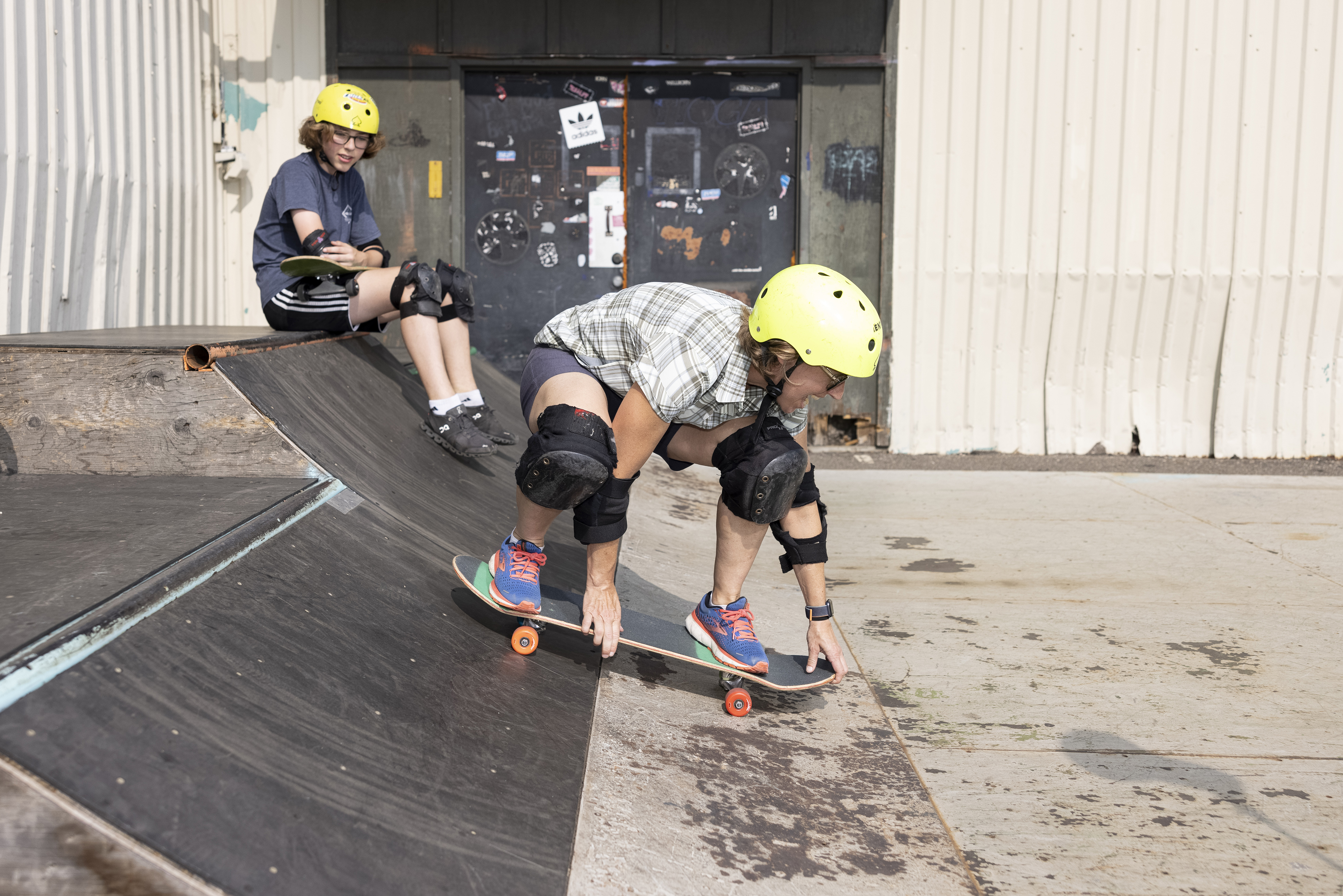 Emily Sohn se desliza con una patineta por una rampa durante una lección de patinaje en tabla mientras su hijo, Zach, de 13 años, la observa en Golden Valley, Minnesota, el 12 de julio de 2021. El patinaje en tabla hará su debut olímpico en los Juegos Olímpicos de Tokio 2020, los cuales fueron pospuestos. (Jenn Ackerman/The New York Times).