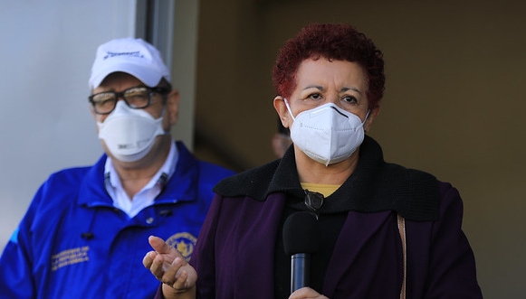 La ministra de Salud Amelia Flores en declaraciones a la prensa mientras el presidente Alejandro Giammattei la observa. (Foto Prensa Libre: Presidencia)