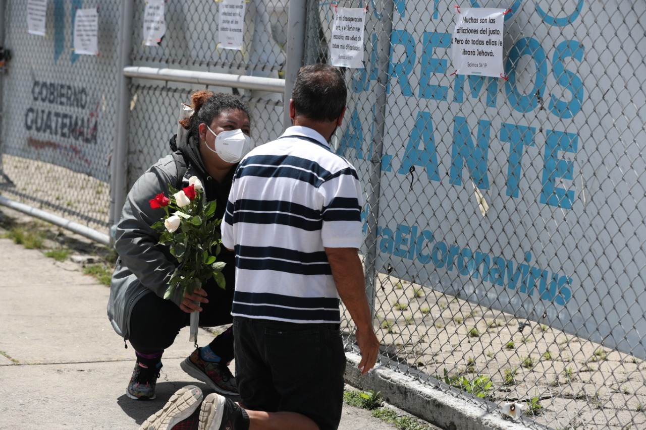 Abigail Martínez Mejía, quién perdió a su madre a causa del covid-19, le obsequia una rosa a Joaquín Álvarez, quien junto a su esposa Maricela llegan todos los días al Parque de la Industria a orar por la salud de uno de sus hijos. (Foto Prensa Libre: María Renée Barrientos)