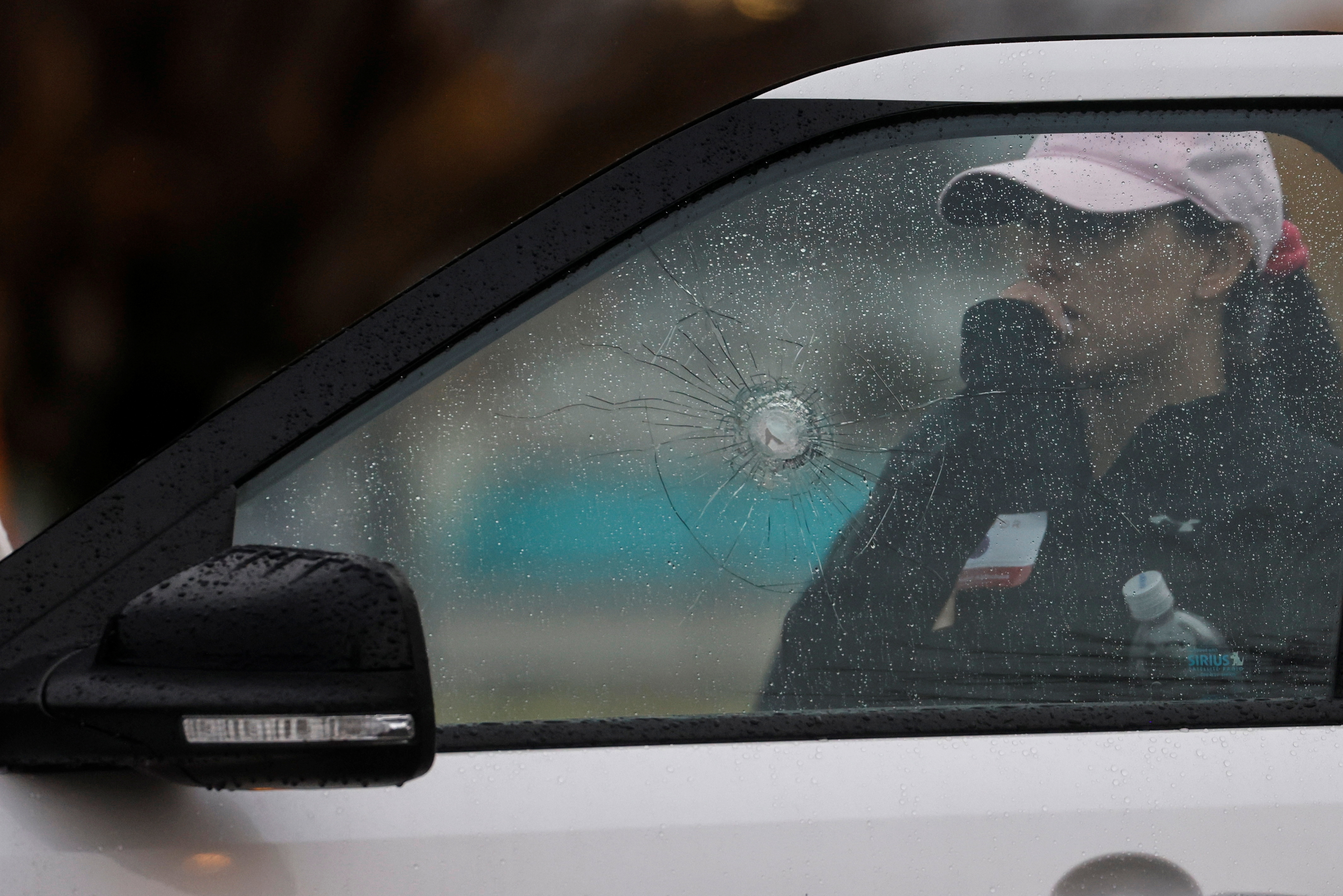 A woman stands behind a car with shattered glass near the scene of a shooting at the Boise Towne Square shopping mall in Boise, Idaho, U.S., October 25, 2021. REUTERS/Shannon Stapleton