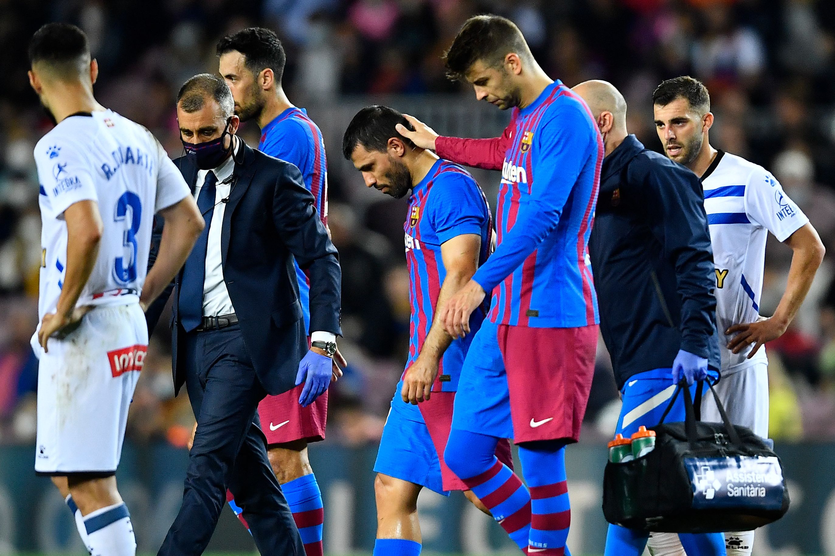 El jugador del Barcelona Gerard Pique (centro derecha) consuela a su compañero Kun Aguero mientras este abandona la cancha en el duelo ante el Deportivo Alaves este 30 de octubre en el Camp Nou. (Foto Prensa Libre: AFP)