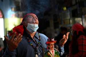 A spiritual guide performs at the Temple of San Simon in the municipality of San Andres Itzapa, Chimaltenango, Guatemala, on October 28, 2021, during a pagan festival to honour to the saint. - Thousands of devotees bring cigarettes and spirits offerings to the saint --not recognized by the Catholic Church-- who is believed to be the protector of the homeless, prostitutes, alcoholics and drug-traffickers. (Photo by Johan ORDONEZ / AFP)