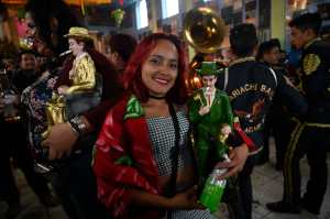 Two women pose with images of San Simon at the Temple of San Simon in the municipality of San Andres Itzapa, Chimaltenango, Guatemala, on October 28, 2021, during a pagan festival to honour to the saint. - Thousands of devotees bring cigarettes and spirits offerings to the saint --not recognized by the Catholic Church-- who is believed to be the protector of the homeless, prostitutes, alcoholics and drug-traffickers. (Photo by Johan ORDONEZ / AFP)