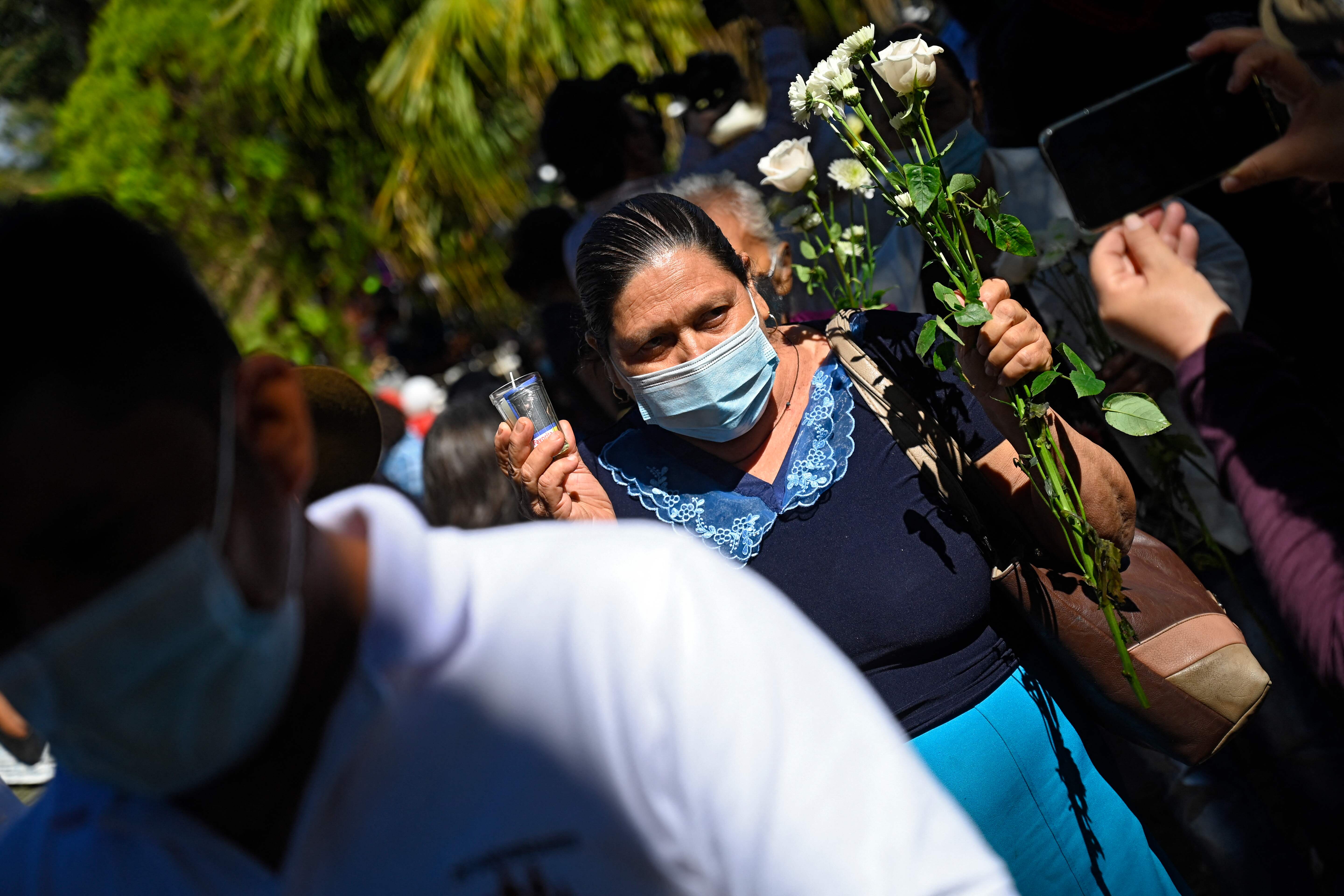 Una mujer sostiene flores blancas durante la conmemoración del 40 aniversario de una masacre en El Mozote, a 200 km al este de San Salvador, el 11 de diciembre de 2021. (Foto: AFP)