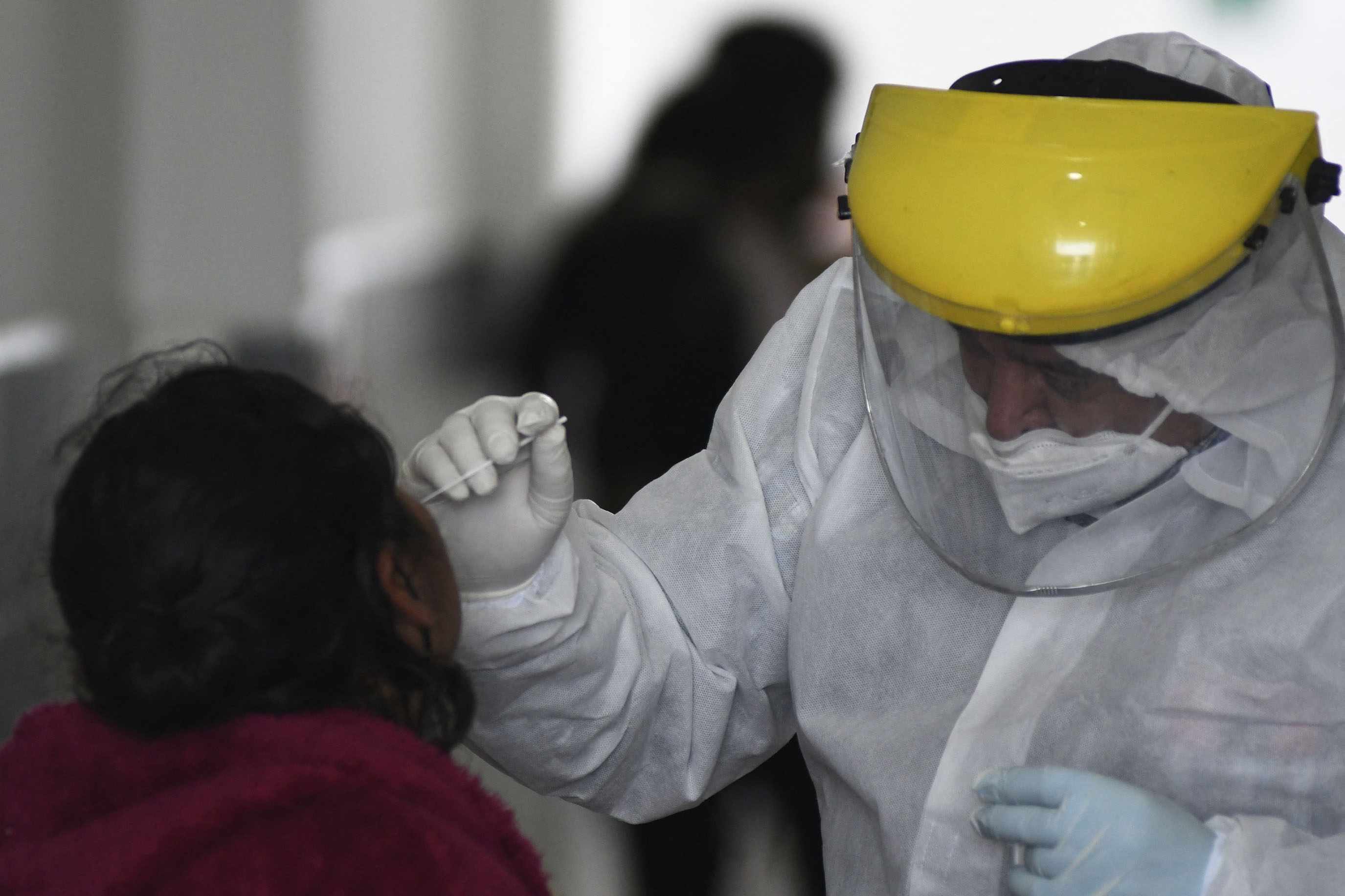 Una trabajadora de salud hace un hisopado en un centro de atención de la capital. Los casos de covid-19 comienzan a repuntar en medio del temor de que ómicron ya está presente en el país. (Foto Prensa Libre: AFP)
