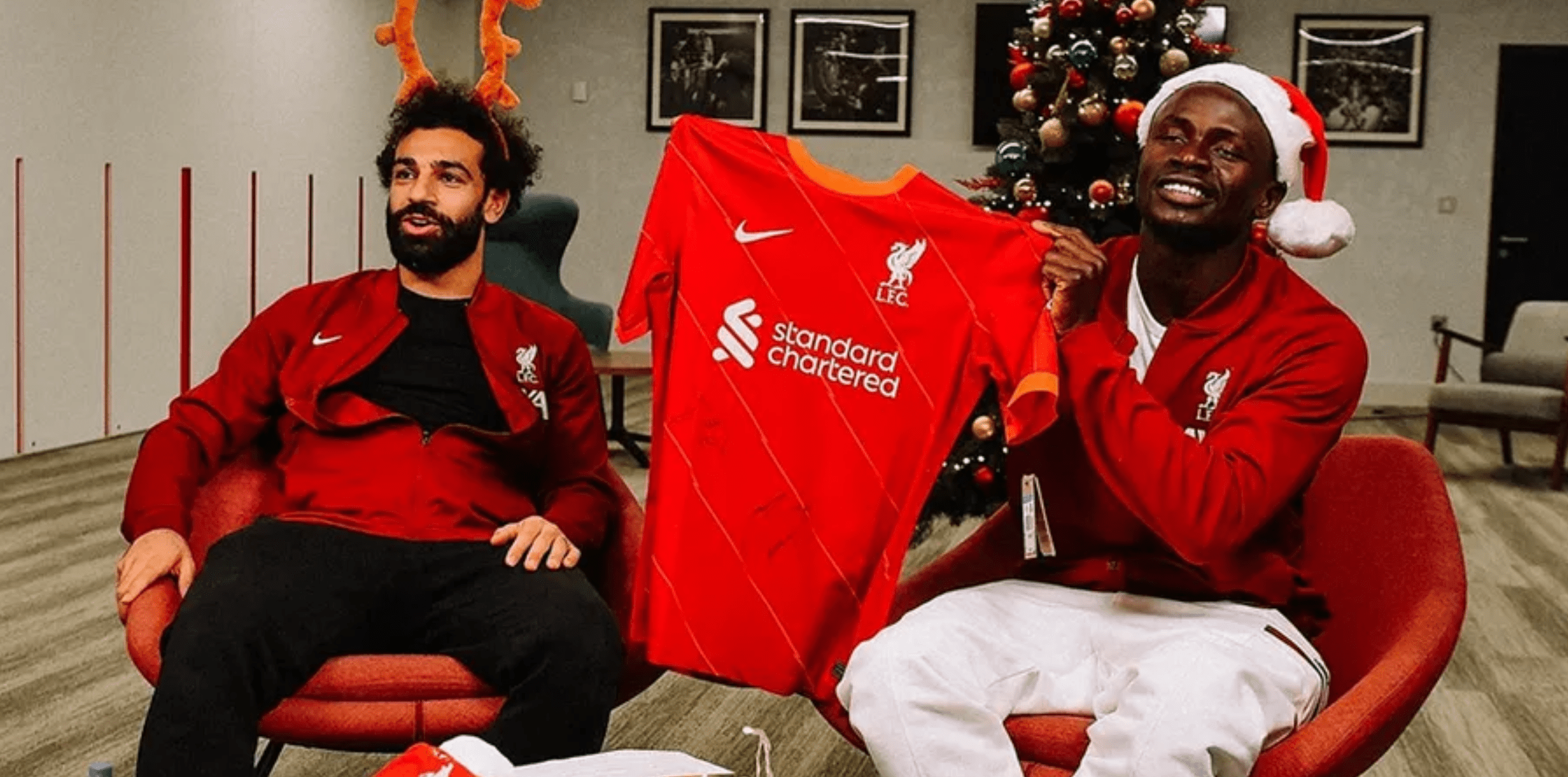 Los jugadores del Liverpool Mohammed Salah y Sadio Mané posan junto a un árbol de navidad mientras sostienen una playera de su equipo. (Foto Prensa Libre: PremierLeague)