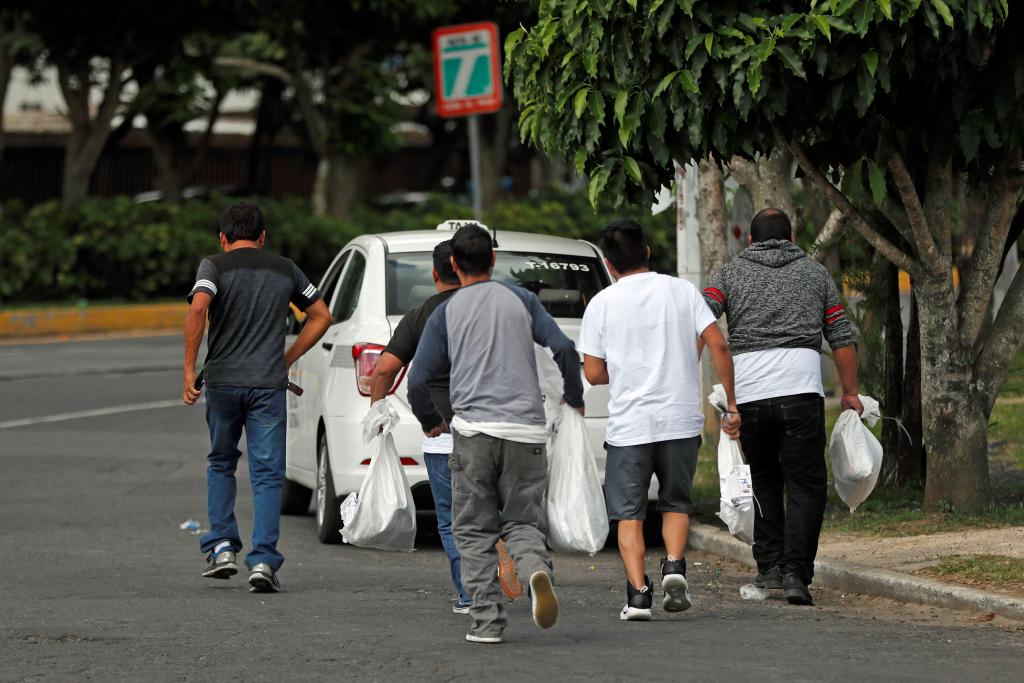 Un grupo de jóvenes sale de las instalaciones de la Fuerza Aérea Guatemalteca con sus pertenencias en bolsas plásticas luego de ser deportados de los Estados Unidos. (Foto Prensa Libre: EFE)
