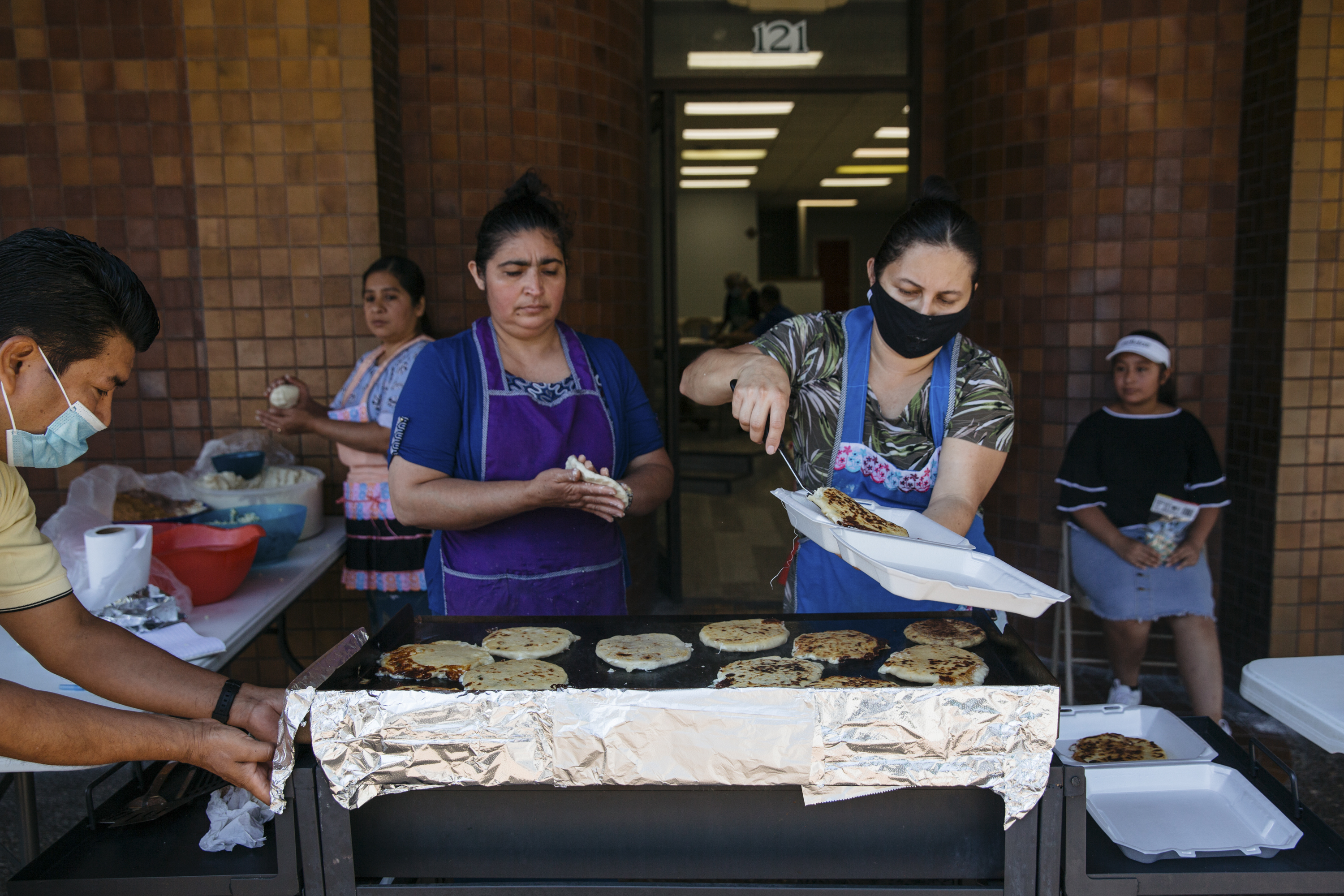 Mujeres de la Iglesia Apostólica hacen y venden pupusas afuera de la iglesia en el centro de Springdale, Arkansas, el 13 de junio de 2021. (Terra Fondriest/The New York Times)