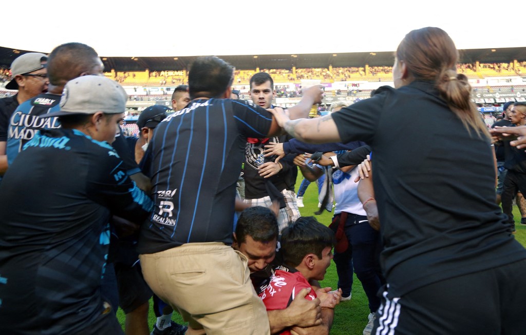 Momentos del hecho violento acontecido el sábado entre aficionados de Querétaro y Atlas. (Foto Prensa Libre: AFP) 