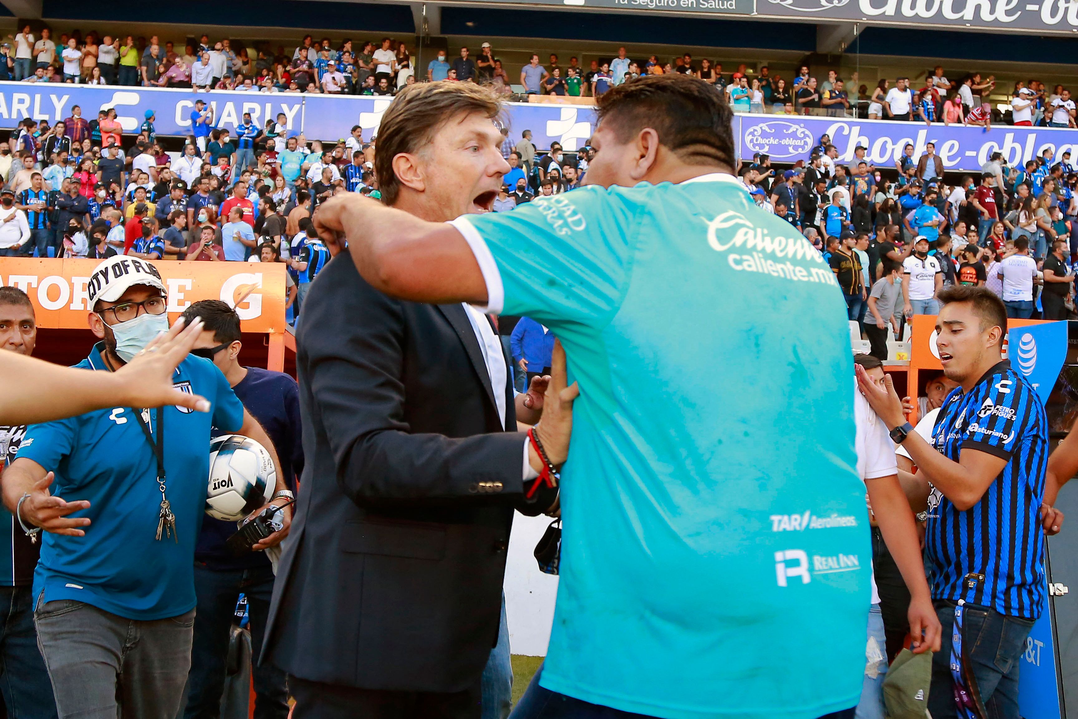 Un aficionado del Querétaro (D) confronta al director técnico de su equipo, el argentino Hernán Cristante (I) durante el juego ante el Atlas que terminó con un enfrentamiento violento entre los fanáticos. Foto Prensa Libre: AFP.