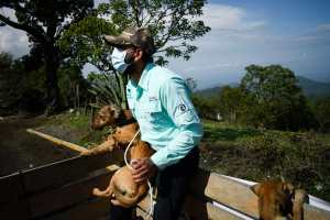 A member of an aminal welfare organization holds a dog before it goes to an improvised shelter during the simulacrum of the eruption of the Pacaya Volcano, at El Rodeo village in San Vicente Pacaya, 55 Km south of Guatemala City on May 6, 2022. - Residents, authorities and animal welfare organizations carried out the first evacuation drill, focused on animal protection, in the face of an eventual eruption of the Pacaya volcano. (Photo by Johan ORDONEZ / AFP)