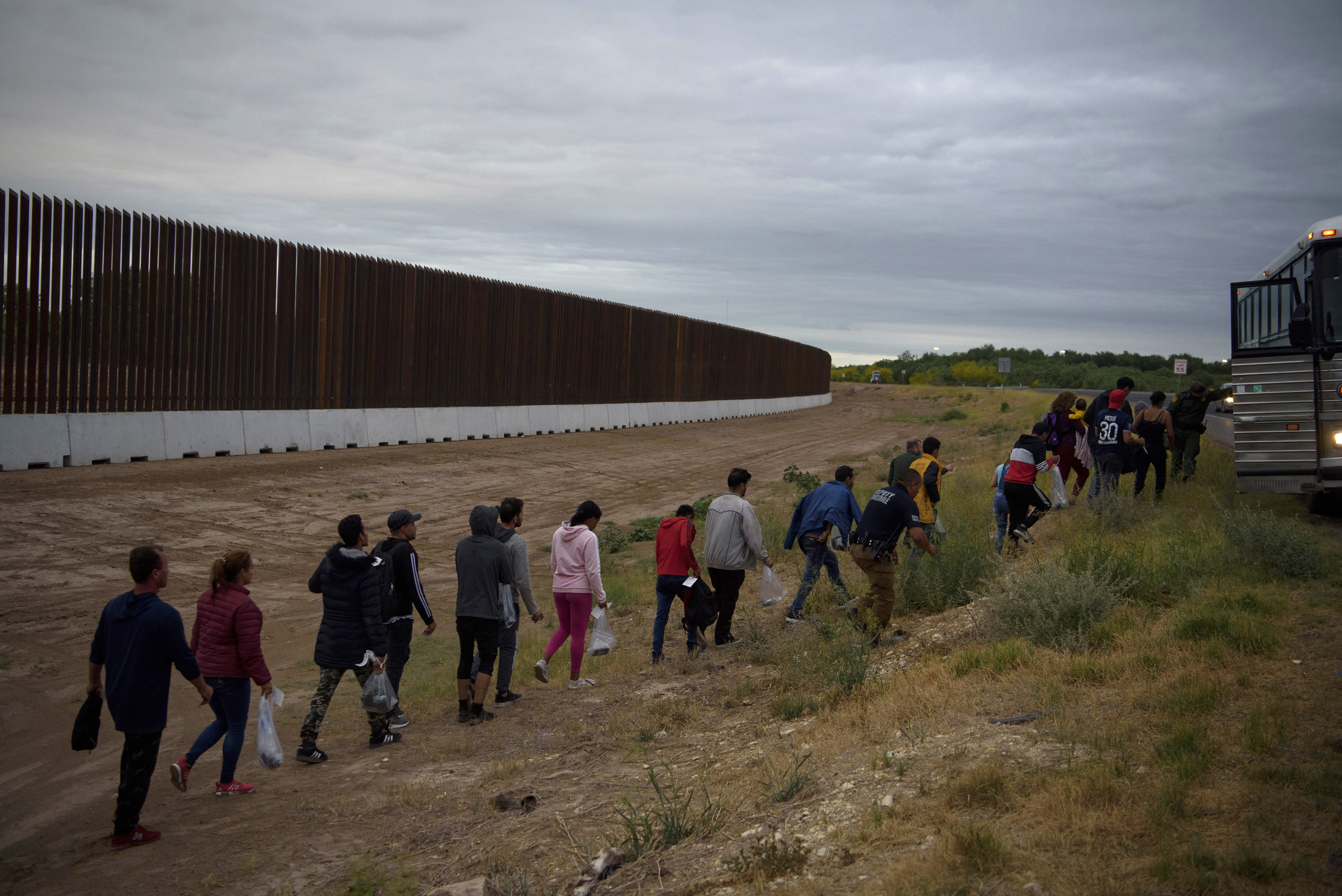 Migrants are loaded onto a bus after crossing the Rio Grande, in Eagle Pass, Texas, April 25, 2022. Gov. Greg Abbott of Texas has pursued an expensive and unusual effort to harden the border, but after a year, there are few signs of progress. (Callaghan O'Hare/The New York Times)