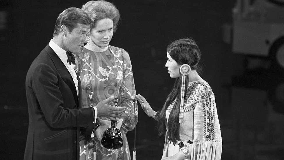 Los actores Roger Moore (izquierda) y Liv Ullman (centro) hacían entrega del premio que fue a recoger Sacheen Littlefeather (derecha), vestida con el traje Apache.
GETTY IMAGES
